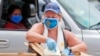 Usando una mascarilla en medio de preocupaciones por el coronavirus, la voluntaria Karen Cooperstein descarga galones de leche para donar al público durante un evento de donación de alimentos de Catholic Charities, en Dallas, Texas, el 2 de julio de 2020.