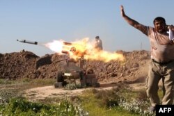 FILE - A fighter from the pro-government Popular Mobilisation (Hashd al-Shaabi) units covers his ears as he sets off a rocket launcher in the village of Taz Khurmatu, on the southern outskirts of the northern Iraqi city of Kirkuk, as they try to recpature the nearby village of al-Bashir from Islamic State (IS) group jihadists on February 16, 2016.