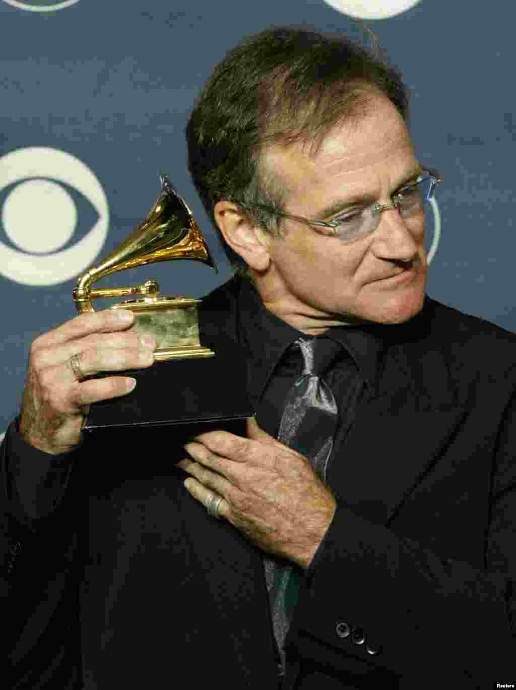 Comedian Robin Williams holds his Grammy Award to his ear as he poses for photographers at the 45th annual Grammy Awards at New York's Madison Square Garden, Feb. 23, 2003. Williams won the Grammy for Best Spoken Comedy Album for "Robin Williams Live 2002."