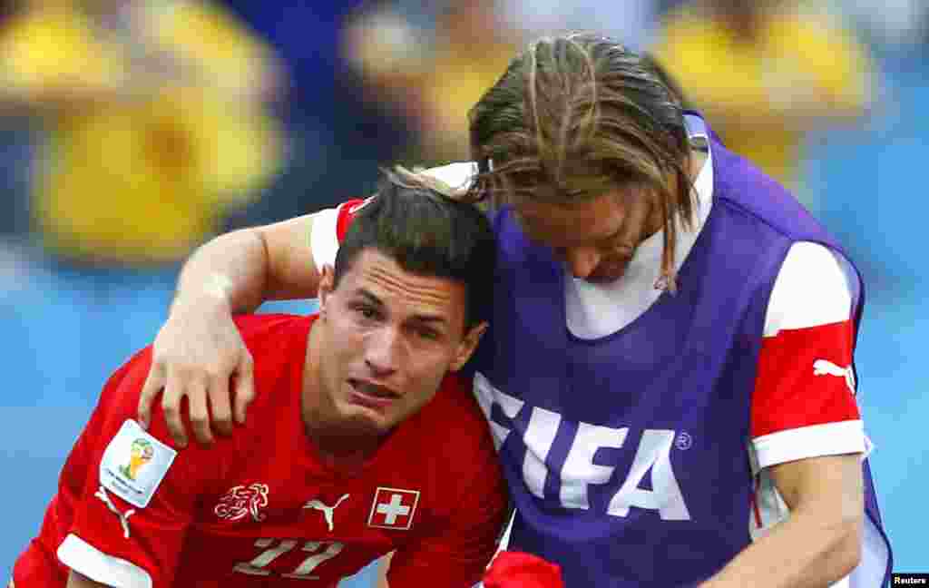 Switzerland's Michael Lang, right, comforts teammate Fabian Schaer after they are defeated by Argentina at the Corinthians arena in Sao Paulo, July 1, 2014.