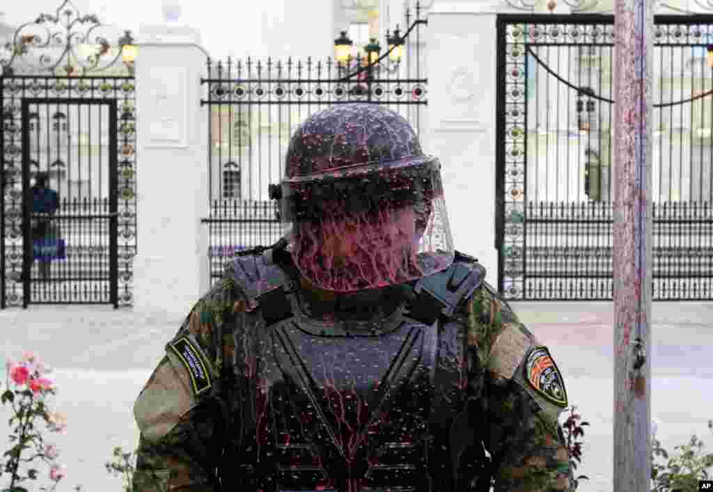 A police officer is splashed after protesters throw balloons filled with paint during an anti-government protest in Skopje, Macedonia, June 6, 2016.