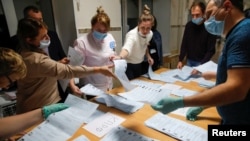 Members of a local electoral commission count ballots at a polling station after polls closed for the municipal elections in Tomsk, Russia, Sept. 13, 2020.