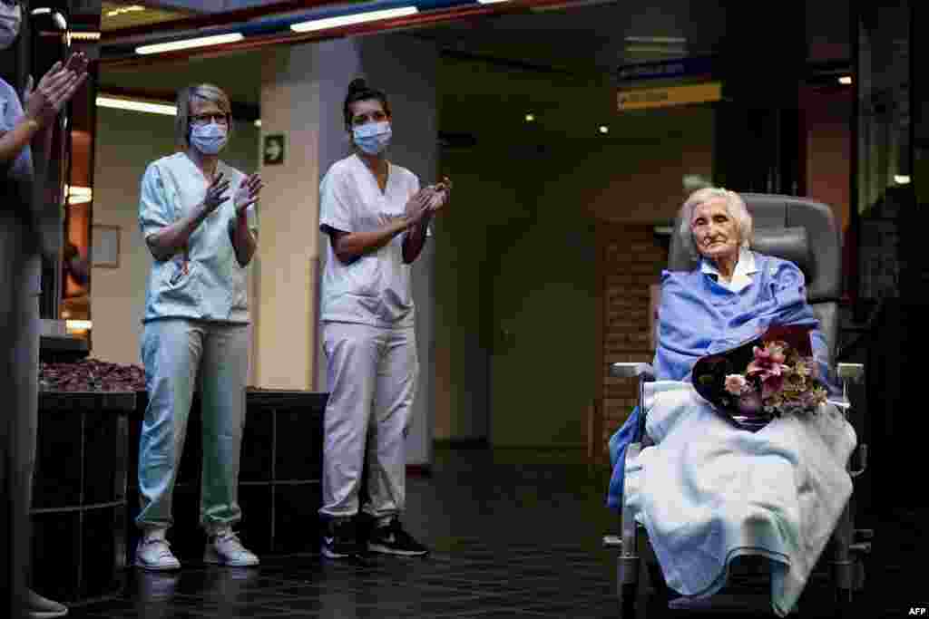 Medical workers clap as 100-year-old patient Julia Dewilde leaves the Bois de l'Abbaye hospital (CHBA) in Seraing, Belgium, after being successfully treated for COVID-19.