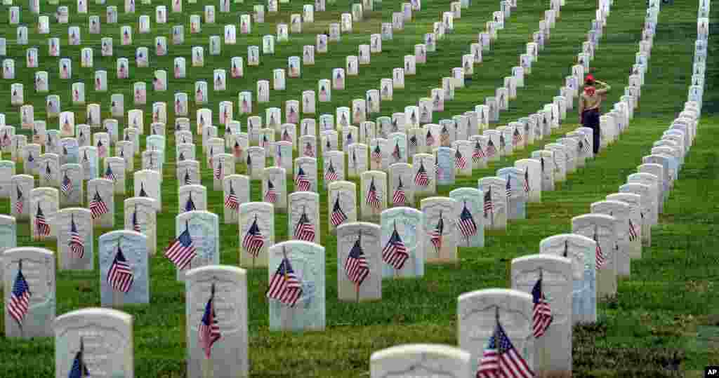 A Boy Scout salutes at the foot of a grave after volunteers placed flags at the Los Angeles National Cemetery, May 28, 2016, in preparation for Memorial Day.
