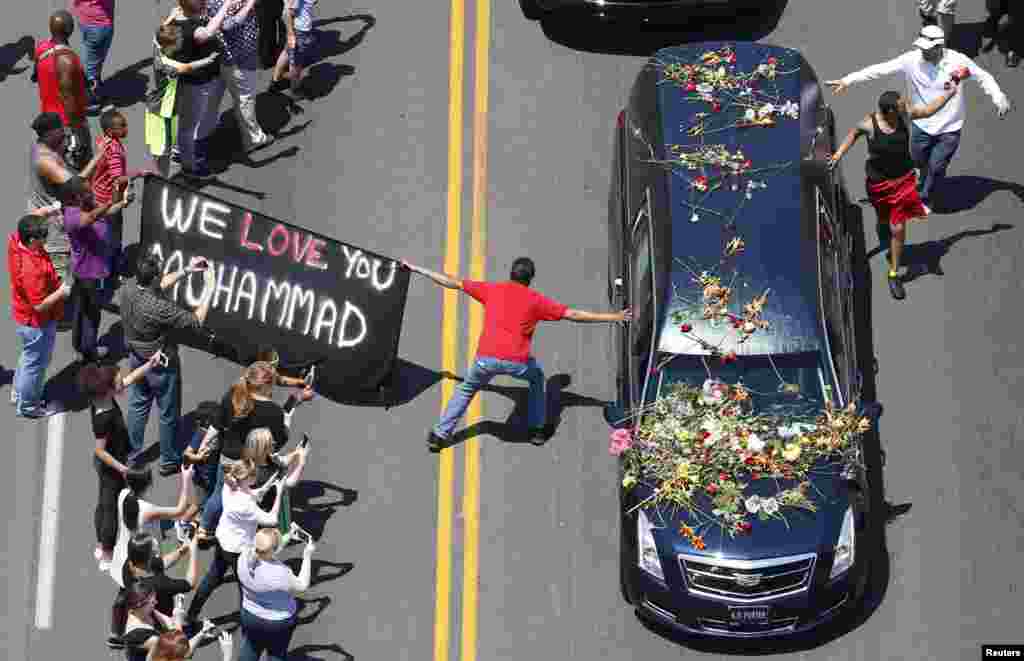 A well-wisher holding a banner touches hearse carrying remains of Muhammad Ali during funeral procession for the three-time heavyweight boxing champion in Louisville, Kentucky, USA.