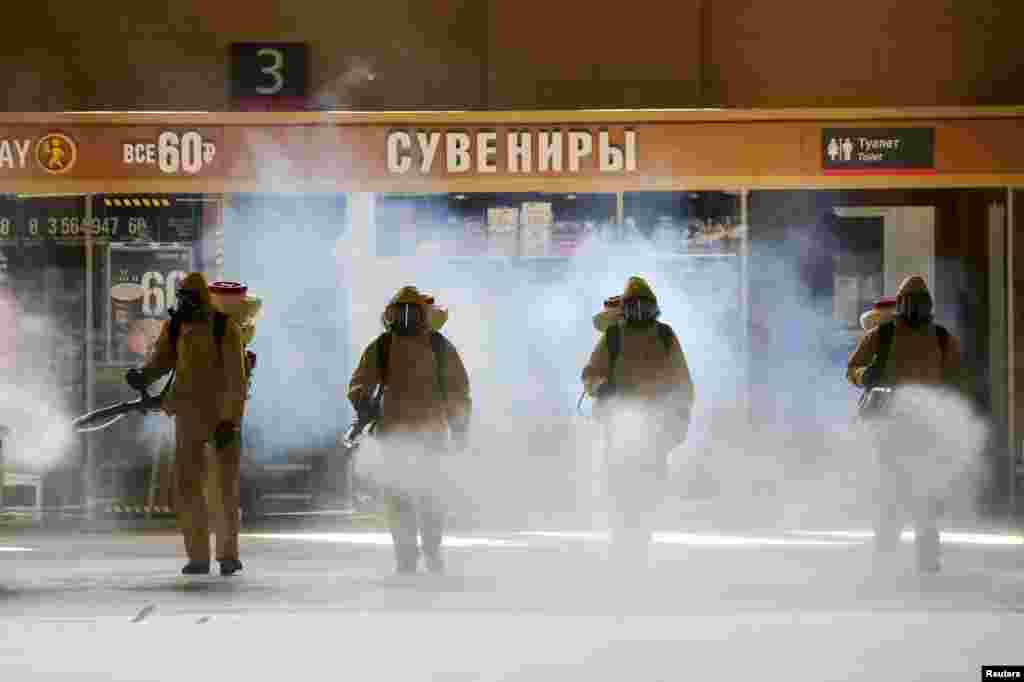 Russia's Emergencies Ministry members wearing personal protective equipment (PPE) spray disinfectant near a gift kiosk at the Kievsky Railway Station amid the outbreak of the coronavirus disease (COVID-19) in Moscow. (Credit: Sandurskaya/Moscow News Agency/Handout)