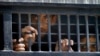 FILE - Detainees peer out from a prison van after their court appearance in Islamabad, Pakistan, Sept. 13, 2014. 