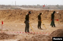 FILE - Mine clearers search for mines and explosive devices at Hammam al-Alil city south of Mosul, Iraq, July 29, 2017.