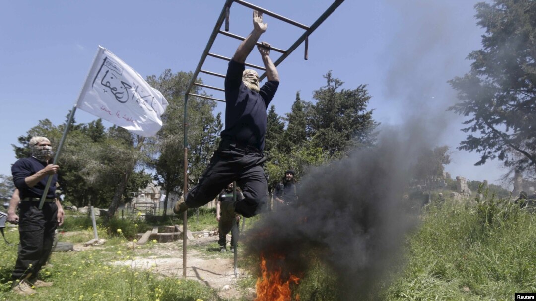 Rebel fighters from 'the First Regiment', part of the Free Syrian Army, swing from bars as they participate in a military training in the western countryside of Aleppo, Syria, May 4, 2015. REUTERS/Hosam Katan