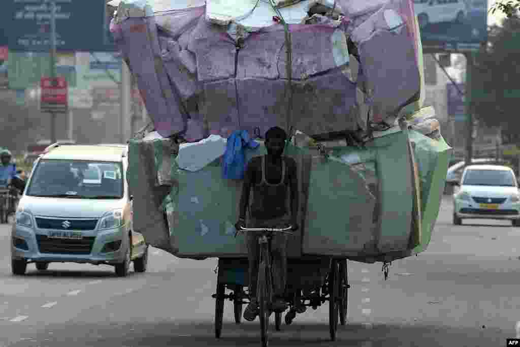 A laborer transports a large load of non bio-degradable waste on the outskirts of New Delhi, India.