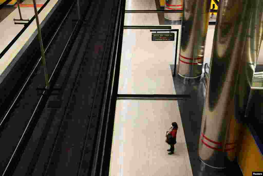 A woman wears a protective face mask at a deserted metro platform during the coronavirus health emergency in Madrid, Spain.