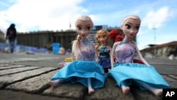ARCHIVO - Una mujer pasa junto a muñecos que representan a víctimas de la violencia infantil, que fueron colocados durante una protesta en la Plaza Bolívar en Bogotá, Colombia, el lunes 30 de noviembre de 2020. 