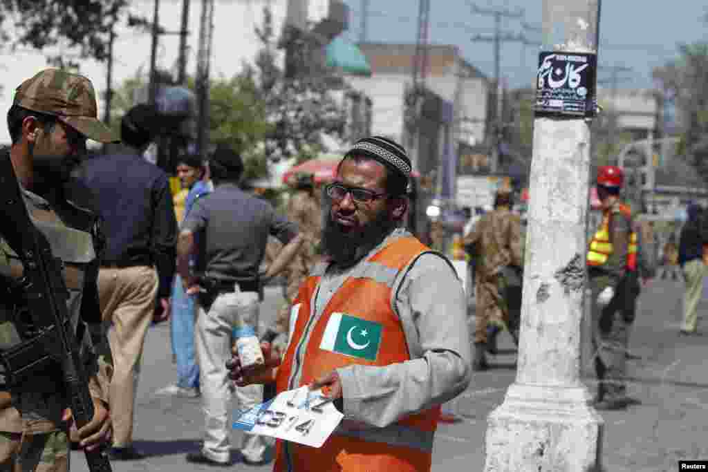 A rescue worker holds a milk bottle and a civilian's vehicle license plate as he collects evidence from the site of a bomb blast in Peshawar, Pakistan, March 29, 2013.