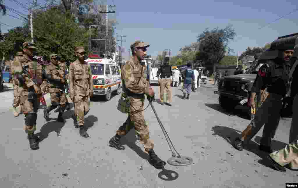A soldier uses a metal detector to survey the site of a bomb blast in Peshawar, Pakistan, March 29, 2013.