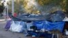 In this Dec. 3, 2019 photo, smoke rises from a wood fire stove at a tent encampment in a public park in Juarez, Mexico, a quarter of a mile away from a border crossing to El Paso, Texas. 