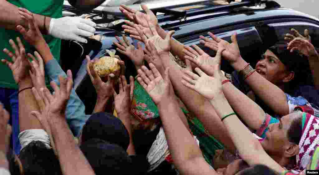 People reach out to get a charity food handout during a lockdown after Pakistan shut all markets, public places and discouraged large gatherings amid an outbreak of the coronavirus disease (COVID-19), in Karachi.