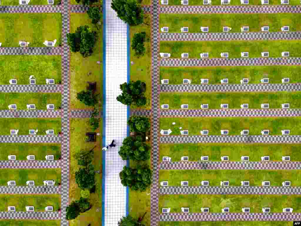 Local people walk between tombs at a military cemetery in Xindian district, New Taipei City, Taiwan. Taiwanese pay their respects to their ancestors during the Qinming Festival between April 2-6.