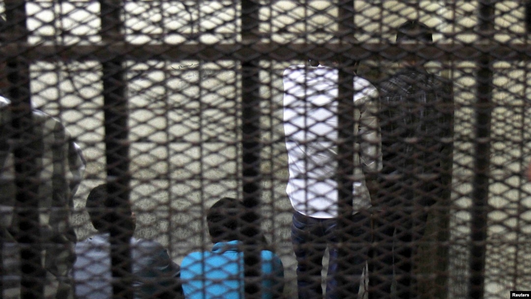FILE - Defendants are seen standing behind bars in a Cairo court.