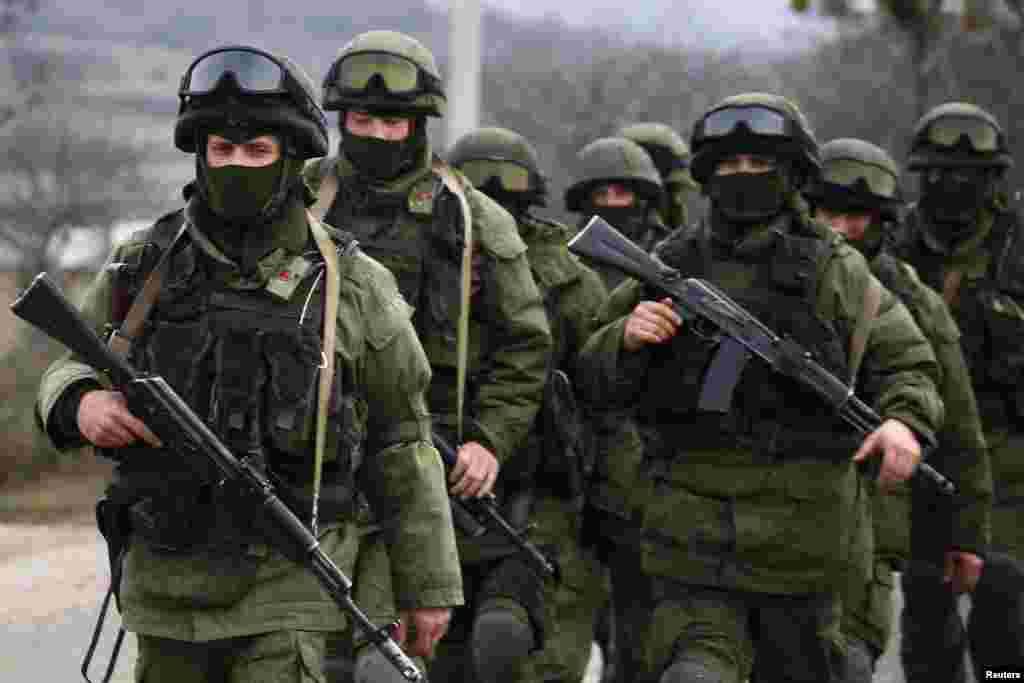 Armed men, believed to be Russian servicemen, march outside an Ukrainian military base in the village of Perevalnoye near the Crimean city of Simferopol, March 9, 2014. 