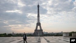 FILE - A man wears a mask to protect against the spread of the coronavirus as he walks along the Trocadero square close to the Eiffel Tower in Paris, April 24, 2020.
