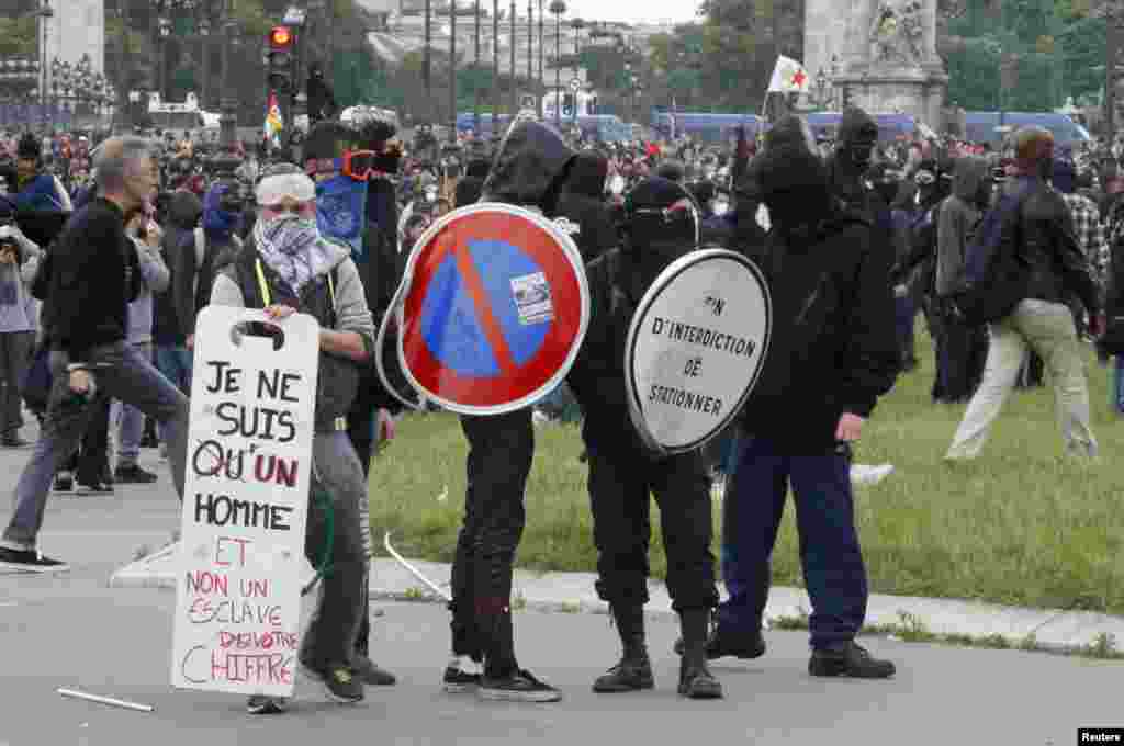 Masked youths face off with French police and gendarmes during a demonstration in Paris as part of nationwide protests against plans to reform French labor laws.