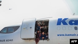 Los afganos se suben a un avión y se sientan junto a la puerta mientras esperan en el aeropuerto de Kabul en Kabul el 16 de agosto de 2021.
