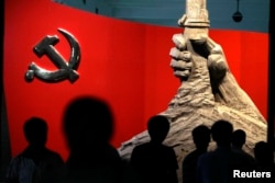 北京軍事博物館展示的中共黨旗與一隻握槍的手的雕塑