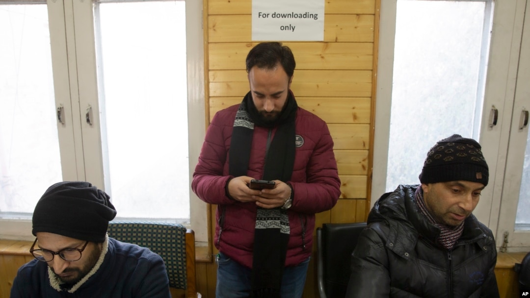 In this Jan. 30, 2020, photo, a Kashmiri journalist, center, browses the internet on his mobile phone inside the media center set up by government authorities in Srinagar, Indian controlled Kashmir. (AP Photo/ Dar Yasin)
