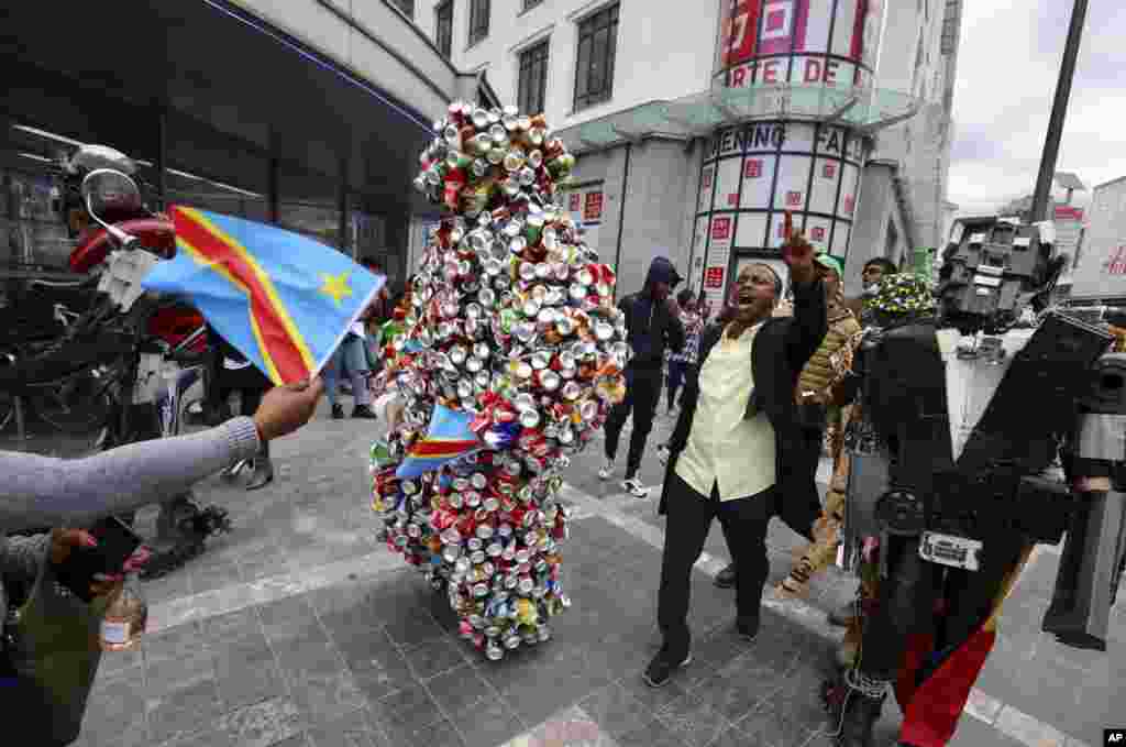 A man and two artists dressed in costume participate in celebrations marking the 60th anniversary of Congo's independence from Belgium in the Brussels district of Matonge.