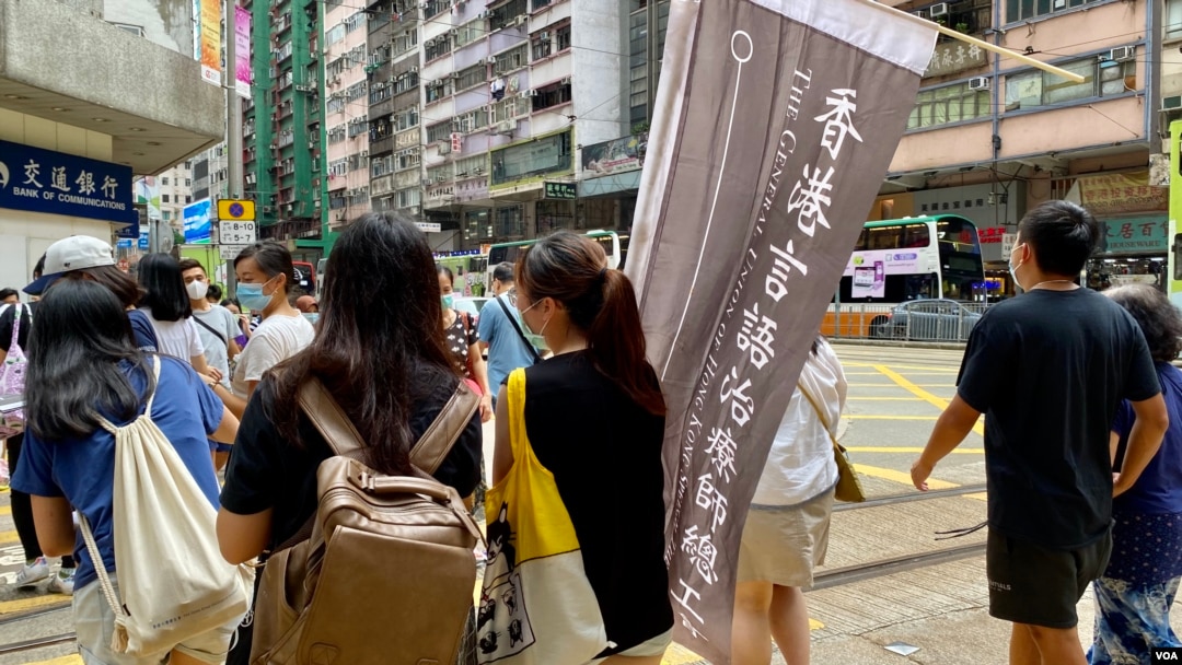 香港言語治療師總工會主席黎雯齡（手持旗幟者）與兩名成員，今年7-1在港島銅鑼灣及灣仔一帶做”流動街站”，呼籲市民繼續發聲，爭取民主 (美國之音/湯惠芸)