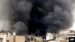 A citizen journalism image provided by Aleppo Media Center, which has been authenticated based on its contents and other AP reporting, shows black smoke rising from buildings due to government forces shelling, in Aleppo, Syria, March 19, 2013.