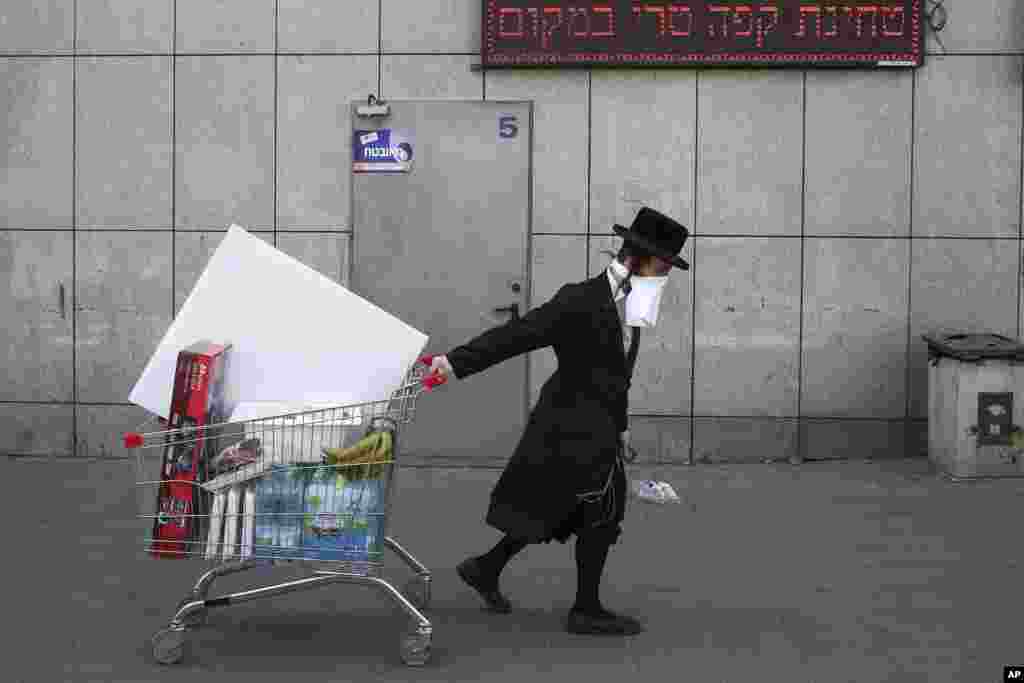 An ultra-Orthodox Jew wears an improvised protective face mask as he pulls a supermarket cart on a mainly deserted street because of the government's measures to help stop the spread of the coronavirus, in Bnei Brak, a suburb of Tel Aviv, Israel.
