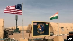 FILE - U.S. and Niger flag are raised side by side at the base camp for air forces and other personnel supporting the construction of Niger Air Base 201 in Agadez, Niger, Apr. 16, 2018.