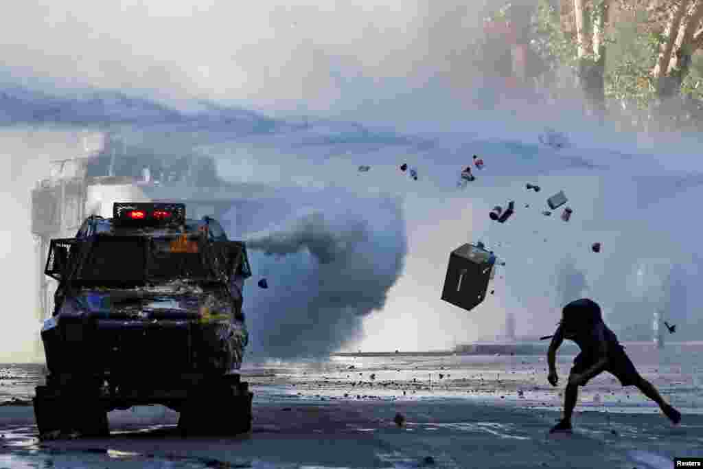 A demonstrator throws items at an armored vehicle during a protest against Chile's government in Santiago, Dec. 30, 2019.