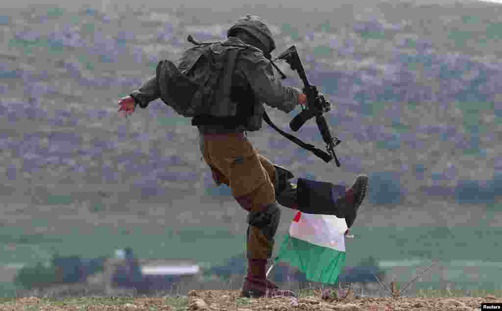An Israeli soldier kicks a Palestinian flag during a protest against the U.S. president Donald Trump’s Middle East peace plan, in Jordan Valley in the Israeli-occupied West Bank.