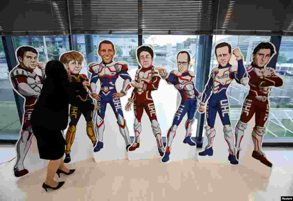 Seorang staf KTT G7 membetulkan letak gambar para pemimpin G7 dengan kostum superhero di Ise, Mie, Jepang.