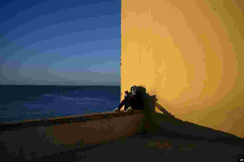 A woman reads by the sea in the city of Cadiz, Spain.