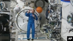 In this image from video made available by NASA, astronaut Nicole Mann shows her dreamcatcher during an interview on, Oct. 19, 2022, the first day of her five-month mission. Mann is the first Native American woman in space. (NASA via AP)