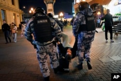 Policajci privode demonstranta tokom protesta protiv mobilizacije, u Moskvi, 21. septembra 2022.