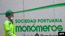 Un trabajador camina junto a la valla de la empresa de fertilizantes Monómeros en la sede de Barranquilla, Colombia, en octubre de 2021. (Foto VOA / Archivo)