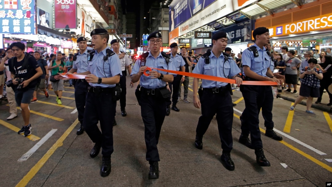Police officers instruct street entertainers and spectators to leave on the last day before the Mong Kok's pedestrian zone closure in Hong Kong, July 29, 2018. 