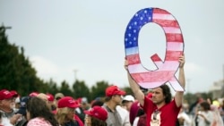 Demonstrant sa znakom Kju pred miting Donalda Trampa (Foto: AP/Matt Rourke)