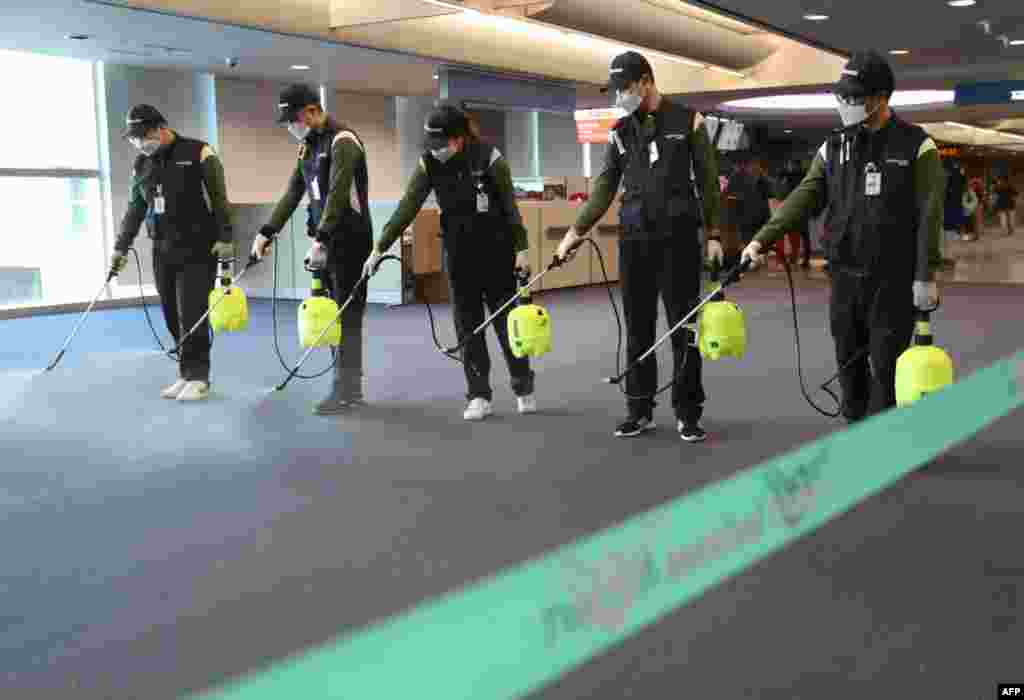 Workers from a cleaning service spray disinfectant at the customs, immigration and quarantine (CIQ) area at Incheon international airport, west of Seoul, South Korea.