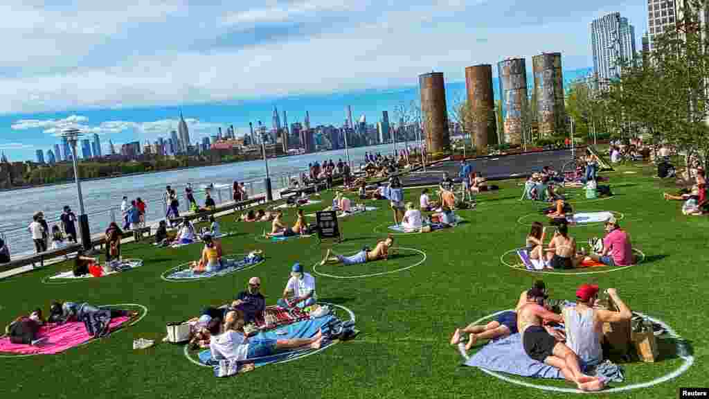 People try to keep social distance as they enjoy a warm day during the outbreak of the coronavirus disease (COVID-19) at Domino Park in Brooklyn, New York, May 16, 2020.