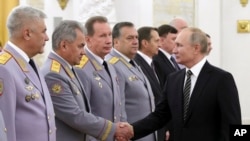 Russian President Vladimir Putin shakes hands with Defense Minister Sergei Shoigu, second left, as he greets senior military officers during a meeting in Moscow, Nov. 6, 2019. 