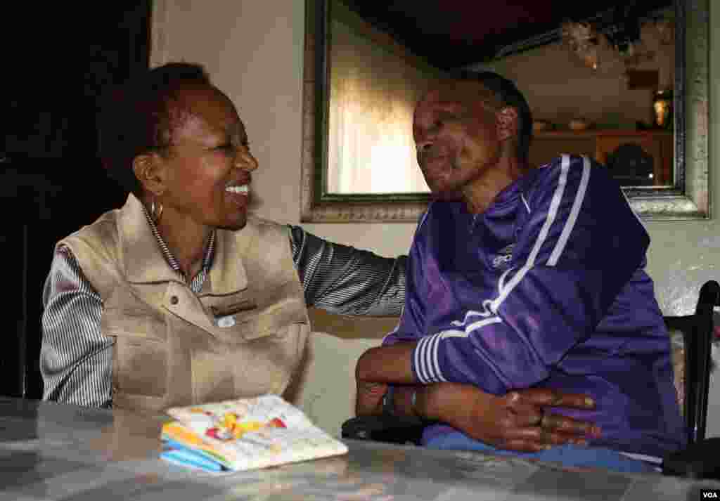 Itumeleng is comforted by palliative care nurse Snowy Nkoana (left). They laugh together over Itumeleng's steadfast dedication to complete a memory book on the table the major events in her life for her children. (Photo by Darren Taylor)