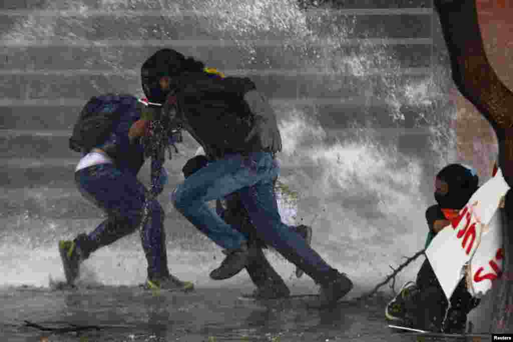Demonstran anti-pemerintah melarikan diri dari semprotan air polisi di Caracas, 20 Maret 2014. Agen intelijen Venezuela menangkap seorang walikota yang beroposisi yang dituduh menyulut protes yang dilakukan dengan kekerasan, sementara seorang lainnya dipenjara selama 10 bulan dalam aksi terbaru meredam para saingan Presiden Nicolas Maduro.