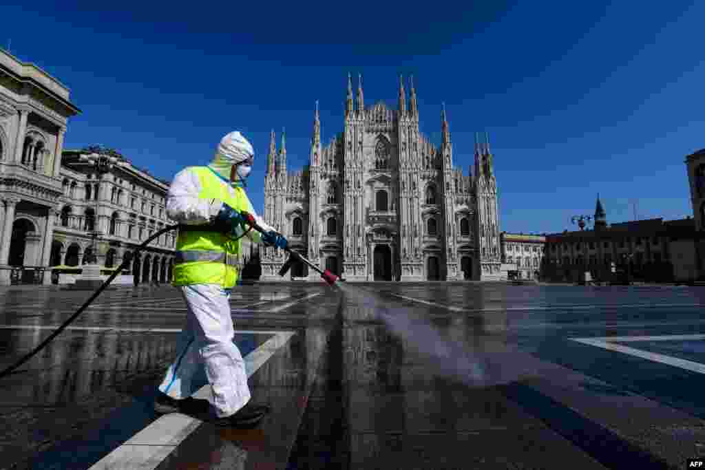 An employee sprays disinfectant on Piazza Duomo in Milan during Italy's lockdown aimed at curbing the spread of the COVID-19 infection.