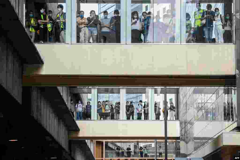 Bystanders watch from footbridges as riot police (not seen) stand guard outside a building below in Hong Kong, as the city's legislature debates a law that bans insulting China's national anthem.