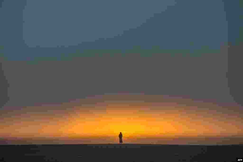 A woman watches the sunset from the beach in Venice, California, April 26, 2020.